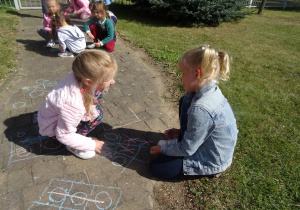 dziewczynki grają w kółko i krzyżyk kreda na chodniku
